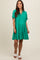 woman wearing a green short sleeve maternity dress with a tiered design and v-neckline