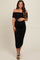 woman wearing a black off-the-shoulder ruched maternity dress and holding her baby bump
