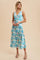woman wearing a floral print midi dress in shades of blue and pastel colors, featuring a V-neck and sleeveless design