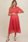 woman wearing a red floral maternity dress with short sleeves and a flowing skirt, holding her baby bump