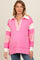woman wearing a pink maternity pullover with a collared neckline and striped sleeve details, showcasing her baby bump