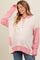 woman wearing a cream and pink oversized maternity hoodie with button detail and a visible baby bump
