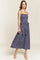 woman wearing a navy blue polka dot midi dress with spaghetti straps and a ruffled hemline