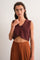woman wearing a maroon cropped knitted top with a v-neck and high-waisted brown pants.