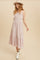 woman wearing a pink floral maxi dress with smocked bodice and tiered skirt, styled with a hat and white ankle boots