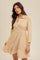 woman wearing a beige striped button-up dress with a ruffled skirt and long sleeves