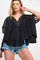 woman wearing a black flowy top with a v-neck and short sleeves paired with denim shorts