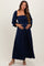 woman wearing a navy blue maternity maxi dress with puff sleeves and ruched bodice, showing her baby bump