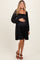 woman wearing a black off-the-shoulder maternity dress and holding her baby bump
