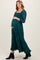 woman wearing a green floral print maternity dress with a square neckline and long sleeves, holding her baby bump