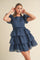 woman wearing a navy blue tiered puff sleeve dress with a checkered pattern and a cinched waist