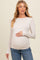 woman wearing a light beige long sleeve maternity top that gathers at the belly, showing her baby bump