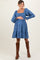 woman wearing a denim blue maternity dress with a square neckline and puff sleeves, holding her baby bump