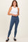 woman wearing a white ribbed crop top and blue high-waisted leggings, smiling with hands on hips