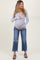 woman wearing a gray long sleeve maternity top and distressed blue jeans, gently holding her baby bump