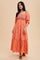 woman wearing a coral maxi dress with smocked bodice and floral embroidery, featuring puff sleeves and a tiered skirt