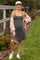 woman wearing a gray striped maternity dress with thin straps and a pink cardigan, showing her baby bump outdoors