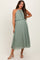 woman wearing a pleated green maternity dress with a halter neck and a flowing silhouette, showing her baby bump