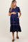 woman wearing a navy blue maternity dress with short sleeves, v-neck, and floral embroidery, highlighting her baby bump