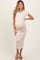 woman wearing a beige short sleeve maternity dress, showcasing her baby bump, standing with one hand on her hip