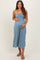 woman wearing a strapless light blue maternity jumpsuit and holding her baby bump