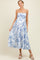 woman wearing a blue floral maternity dress with spaghetti straps and a flowing skirt, showcasing her baby bump
