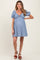 woman wearing a striped blue maternity dress with balloon sleeves and a tie front, showcasing her baby bump