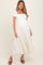 woman wearing a creamy white maternity dress with puff sleeves and a tiered skirt, showcasing her baby bump