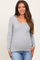 woman wearing a grey long sleeve maternity top with a scoop neckline and a visible baby bump, paired with blue jeans