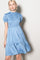 woman wearing a light blue smocked short sleeve dress with a tiered skirt