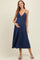 woman wearing a navy blue maternity dress with a v-neck and spaghetti straps, gently holding her baby bump