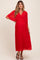 woman wearing a red pleated maternity dress with a V-neck and flutter sleeves, showing her baby bump
