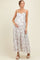 woman wearing a white floral maternity maxi dress with spaghetti straps and holding her baby bump