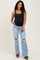 woman wearing a black maternity tank top and distressed light blue maternity jeans with a visible baby bump