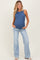 woman wearing a dark blue maternity tank top and light blue flared jeans, showing her baby bump
