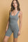 woman wearing a gray ribbed sleeveless bodysuit with a scoop neckline and fitted design