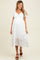 woman wearing a white maternity dress with puff sleeves and a tiered skirt, showing a baby bump