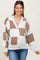 woman wearing a beige and white color block maternity cardigan and showing her baby bump