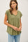 woman wearing an olive green short sleeve v-neck top with a relaxed fit and jeans