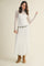 woman wearing a white lace long sleeve maxi dress with a silver belt and brown heeled boots