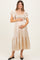 woman wearing a beige polka dot maternity dress with flutter sleeves and a fitted bodice, showing her baby bump