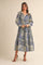 woman wearing a long-sleeve, blue and cream patterned maxi dress with a ruffled neckline and tied waist