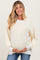woman wearing a cream and light yellow striped maternity sweater and holding her baby bump