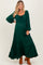 woman wearing a dark green maternity dress with long sleeves and ruffled hem, showcasing her baby bump
