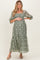 woman wearing a green floral embroidered maternity dress and holding her baby bump