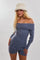 woman wearing a light blue off-shoulder long sleeve romper with ribbed detailing and a cream-colored hat