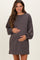 woman wearing a dark grey maternity dress with long sleeves and pockets, holding her baby bump
