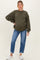 woman wearing an olive green oversized maternity sweatshirt and blue distressed jeans, with a visible baby bump