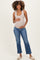 woman wearing a light beige ribbed maternity tank top and distressed blue maternity jeans, holding her baby bump