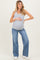 woman wearing a gray maternity tank top and wide-leg blue jeans, holding her baby bump